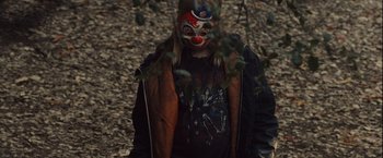 Movie still from “Halloween” (2007), directed by Rob Zombie – A man with a clown mask on his face; Medium shot, High angle