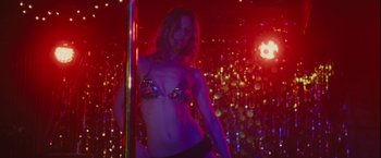 Movie still from “Halloween” (2007), directed by Rob Zombie – A woman in a bikini standing next to a pole in a room; Medium shot, Low angle