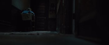 Movie still from “Halloween” (2007), directed by Rob Zombie – A person sitting on a chair in a dark room; Wide shot, High angle