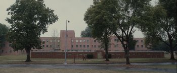 Movie still from “Halloween” (2007), directed by Rob Zombie – A person walking down a street near a building; Extreme Wide shot, Low angle
