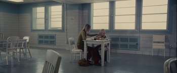 Movie still from “Halloween” (2007), directed by Rob Zombie – Two women sitting at a white table with papers; Wide shot, High angle