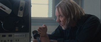 Movie still from “Halloween” (2007), directed by Rob Zombie – An older man with long white hair is holding a microphone; Close Up shot, Over the shoulder angle