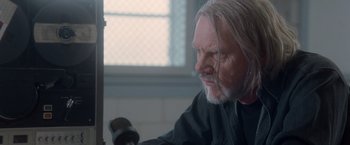 Movie still from “Halloween” (2007), directed by Rob Zombie – An older man with long white hair is sitting in front of a window; Close Up shot, Over the shoulder angle