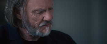 Movie still from “Halloween” (2007), directed by Rob Zombie – An older man with a gray beard looking to his left; Close Up shot, Low angle