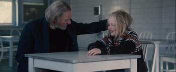 Movie still from “Halloween” (2007), directed by Rob Zombie – A man and a girl sitting at a table; Medium shot, Over the shoulder angle