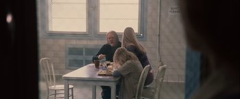 Movie still from “Halloween” (2007), directed by Rob Zombie – A man sitting at a table with two women and a child; Wide shot, Over the shoulder angle