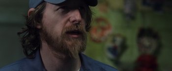 Movie still from “Halloween” (2007), directed by Rob Zombie – A person with a beard wearing a hat; Close Up shot, Over the shoulder angle