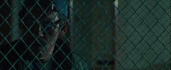 Movie still from “Halloween” (2007), directed by Rob Zombie – A man wearing a blue hat and glasses behind a fence; Close Up shot, Low angle
