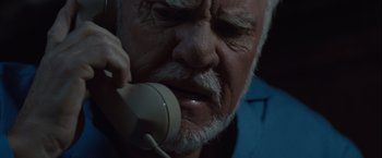 Movie still from “Halloween” (2007), directed by Rob Zombie – An older man talking on a phone while wearing a blue shirt; Extreme Close Up shot, Low angle