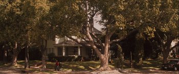 Movie still from “Halloween” (2007), directed by Rob Zombie – Two people sitting under a large tree in front of a house; Extreme Wide shot, High angle