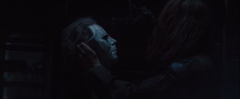 Movie still from “Halloween” (2007), directed by Rob Zombie – A person is putting makeup on another person's face in the dark; Close Up shot, Over the shoulder angle