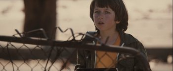 Movie still from “Halloween” (2007), directed by Rob Zombie – A young boy standing in front of a chain link fence; Close Up shot, Over the shoulder angle