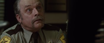 Movie still from “Halloween” (2007), directed by Rob Zombie – A person wearing a police uniform; Close Up shot, Over the shoulder angle