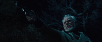 Movie still from “Halloween” (2007), directed by Rob Zombie – An older man holding a camera in a dark forest; Close Up shot, Low angle
