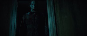 Movie still from “Halloween” (2007), directed by Rob Zombie – A statue of michael myers in a dark room; Medium shot, Low angle