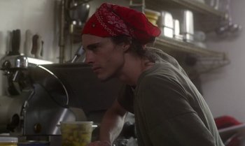 Movie still from “Ham on Rye” (2019), directed by Tyler Taormina – A young man wearing a red bandanna is leaning on a counter; Close Up shot, Low angle