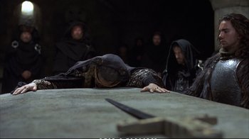 Movie still from “Hamlet” (1990), directed by Franco Zeffirelli – A group of people standing next to each other in front of a table; Medium shot, High angle