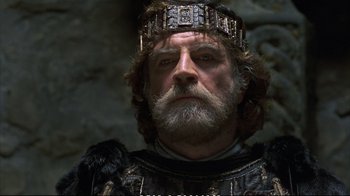 Movie still from “Hamlet” (1990), directed by Franco Zeffirelli – A person with a beard wearing a crown; Close Up shot, Low angle