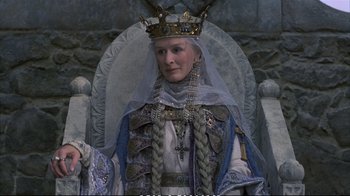 Movie still from “Hamlet” (1990), directed by Franco Zeffirelli – A woman wearing a crown sitting on a throne; Medium shot, High angle