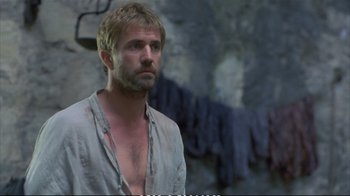 Movie still from “Hamlet” (1990), directed by Franco Zeffirelli – A man with a goatee is standing in front of rocks; Medium shot, Low angle