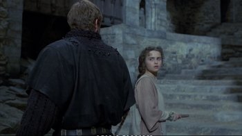 Movie still from “Hamlet” (1990), directed by Franco Zeffirelli – A man and a woman standing next to each other in front of a stone wall; Medium shot, Over the shoulder angle