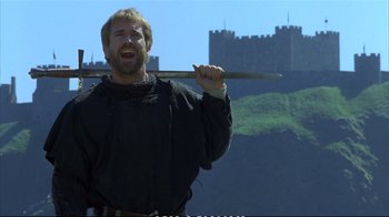 Movie still from “Hamlet” (1990), directed by Franco Zeffirelli – A man holding a wooden stick in front of a castle; Medium shot, Low angle