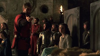 Movie still from “Hamlet” (1990), directed by Franco Zeffirelli – A group of people dressed in medieval garb in a room; Medium shot, Over the shoulder angle