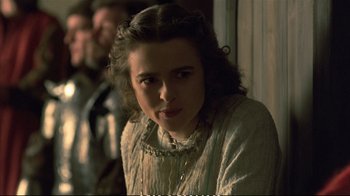 Movie still from “Hamlet” (1990), directed by Franco Zeffirelli – A young woman in a white dress is standing in front of a window; Close Up shot, Over the shoulder angle