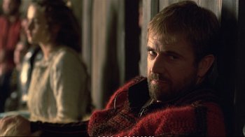 Movie still from “Hamlet” (1990), directed by Franco Zeffirelli – A man sitting in a chair wearing a red sweater; Close Up shot, Over the shoulder angle