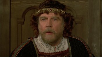 Movie still from “Hamlet” (1990), directed by Franco Zeffirelli – A person with a beard wearing a crown; Close Up shot, High angle