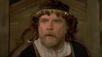 Movie still from “Hamlet” (1990), directed by Franco Zeffirelli – A man with a beard wearing a crown; Close Up shot, Over the shoulder angle