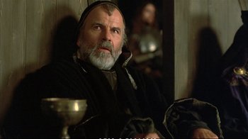 Movie still from “Hamlet” (1990), directed by Franco Zeffirelli – An older man sitting in a chair in a room; Close Up shot, Low angle