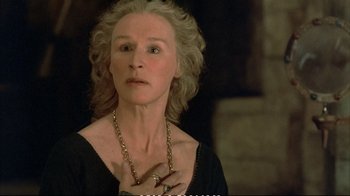 Movie still from “Hamlet” (1990), directed by Franco Zeffirelli – An older woman wearing a necklace and a black dress; Close Up shot, High angle