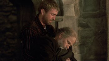 Movie still from “Hamlet” (1990), directed by Franco Zeffirelli – A man and a man with a beard are sitting together; Medium shot, Over the shoulder angle