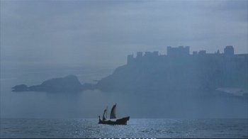 Movie still from “Hamlet” (1990), directed by Franco Zeffirelli – A boat sailing on a body of water with a castle in the background; Extreme Wide shot, Low angle