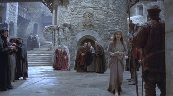 Movie still from “Hamlet” (1990), directed by Franco Zeffirelli – A group of people standing in front of a stone building; Wide shot, Low angle