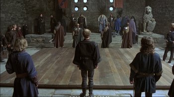 Movie still from “Hamlet” (1990), directed by Franco Zeffirelli – A group of people dressed in medieval garb on a stage; Wide shot, High angle