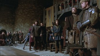 Movie still from “Hamlet” (1990), directed by Franco Zeffirelli – A group of people standing in front of a wall; Wide shot, Low angle