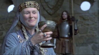 Movie still from “Hamlet” (1990), directed by Franco Zeffirelli – A woman holding a goblet in front of a man in armor; Close Up shot, Low angle