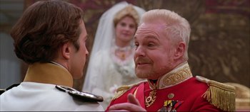 Movie still from “Hamlet” (1996), directed by Kenneth Branagh – A man in a red jacket talking to another man in a white suit; Close Up shot, Over the shoulder angle