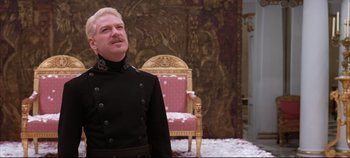 Movie still from “Hamlet” (1996), directed by Kenneth Branagh – A man standing in front of a chair in a room; Medium shot, Low angle