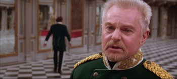 Movie still from “Hamlet” (1996), directed by Kenneth Branagh – An older man in a military uniform stares at the camera; Close Up shot, Over the shoulder angle