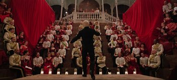 Movie still from “Hamlet” (1996), directed by Kenneth Branagh – A man standing in front of a crowd of people in front of a staircase; Wide shot, Low angle