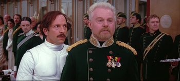 Movie still from “Hamlet” (1996), directed by Kenneth Branagh – A man in a military uniform stands next to another man in a white suit; Medium shot, Low angle