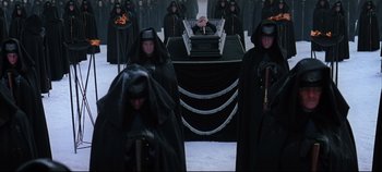 Movie still from “Hamlet” (1996), directed by Kenneth Branagh – A group of people dressed in black standing in front of an altar; Wide shot, High angle
