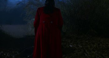 Movie still from “Hanh Phúc Máu” (2022), directed by Nguyen Minh Chung – A woman in a red coat standing in the dark; Wide shot, High angle