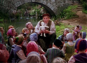 Movie still from “Hans Christian Andersen” (1952), directed by Charles Vidor – A group of children sitting in front of a man holding a puppet; Wide shot, High angle