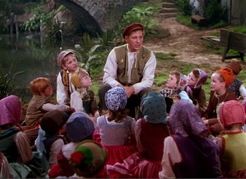 Movie still from “Hans Christian Andersen” (1952), directed by Charles Vidor – A group of children sitting in a circle around a man; Wide shot, High angle
