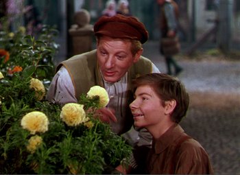 Movie still from “Hans Christian Andersen” (1952), directed by Charles Vidor – A man and a young boy looking at flowers; Medium shot, Over the shoulder angle