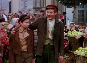 Movie still from “Hans Christian Andersen” (1952), directed by Charles Vidor – A man and a boy are standing in front of a crowd of people; Medium shot, Over the shoulder angle
